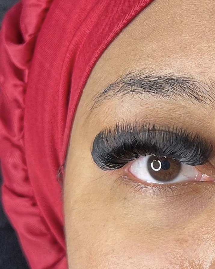 Volle donkere wimperextensions bij een klant met een rode hoofddoek