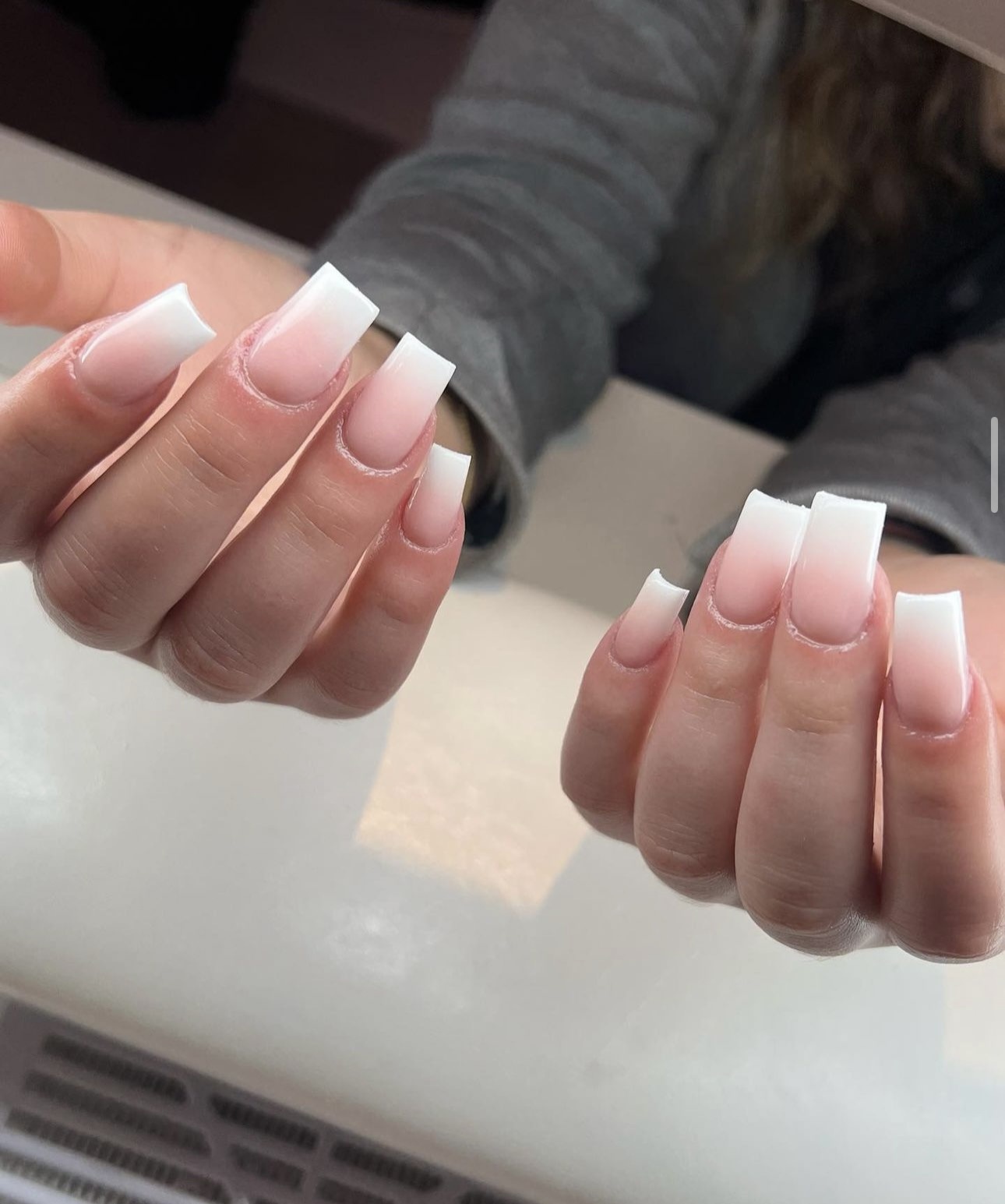Twee handen met lange acryl French ombré nagels