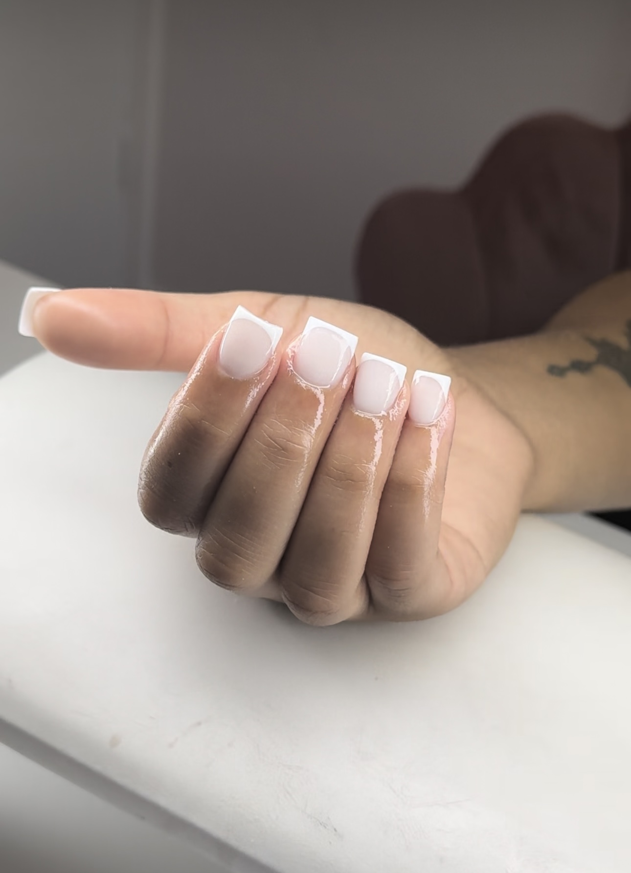 Acryl French ombré nagels op een hand, rustend op de handsteun